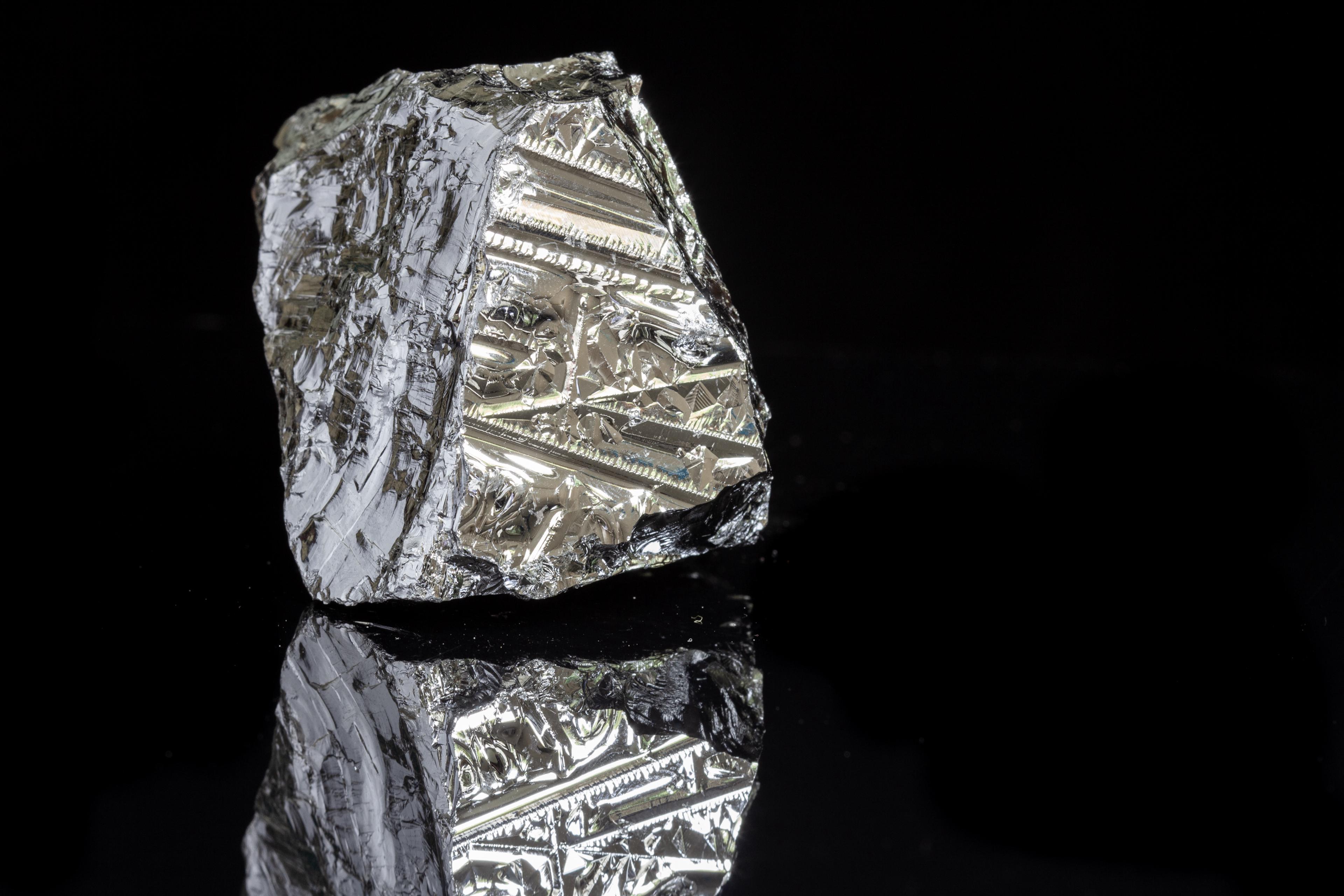 A block of silicon (also known as a mono-crystal) placed on a plain black background and photographed in HD to make its rich, reflective and complex surface visible.